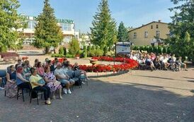 Na krzesłach po ubu stronach fontanny siedzi publiczność i słucha czytania.