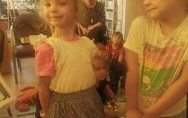 Stoją dwie dziewczynki o blond włosach. Jedna z nich dumnie pokazuje swoją sp&oacute;dniczkę w kropeczki.