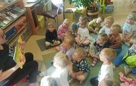 Dzieci siedzą w bibliotece na dywanie, a Pani z biblioteki czyta im bajkę o jesieni.