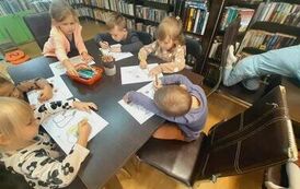 Dzieci przy stołach kolorują motywy jesienne.
