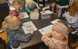 Dzieci przy stołach kolorują motywy jesienne.