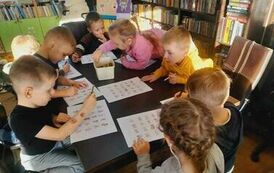 Dzieci siedzą przy stole i robią karty pracy.