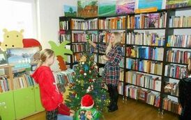 Dwie dziewczynki i ich Pani przywieszają ozdoby na choinkę.