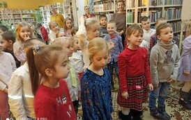 Dzieci stoją na dywanie i patrzą w stronę Szymona G&oacute;ralczyka.