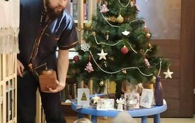 Szymon pokazuje dzieciom stary młynek do kawy. W tle widać choinkę.