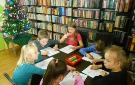 Dzieci siedzą przy stole i uzupełniają karty pracy.