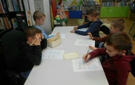 Chłopcy siedzą przy białym stole i robią świąteczne karty pracy.