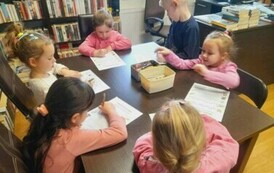 Dzieci siedzą przy stole i robią karty pracy.