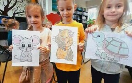 Dwie dziewczynki i chłopiec po środku pokazują swoje pokolorowane zwierzątka.