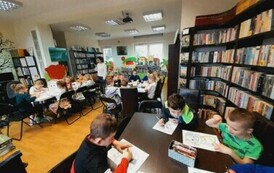 Przy stołach siedzą dzieci i robią karty pracy i kolorują zwierzątka. Z tyłu widać nauczyciela robiącego zdjęcie.