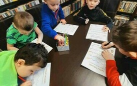 Przy stole siedzą chłopcy i i robią karty pracy.