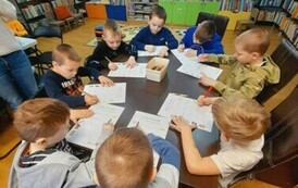 Przy stole siedzą chłopcy i robią kartę pracy.