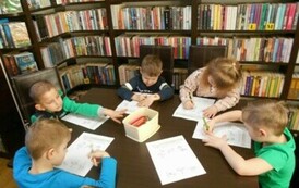 Dzieci siedzą przy stole i robią karty pracy.