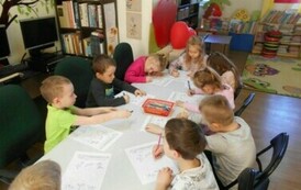 Dzieci siedzą przy stole i robią karty pracy.
