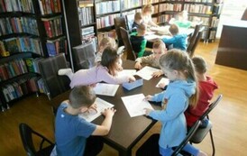 Dzieci siedzą przy stołach i robią karty pracy dotyczące zbliżającej się wiosny.