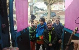 Dzieci oglądają wnętrze busa nagraniowego.Z przodu stoją dwie gitary elektryczne..