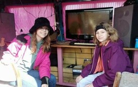 W busie przy telewizorze siedzą dwie dziewczyny. Z tyłu widać sprzęt nagraniowy.