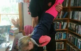 Strażak trzyma dziewczynkę na rękach głową do podłogi z nogami ku g&oacute;rze.