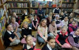 Dzieci siedzą na podłodze w Bibliotece i słuchają strażaka, kt&oacute;ry im opowiada o udzielaniu pierwszej pomocy.