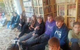 Młodzież siedzi na dywanie i patrzy w stronę autora.