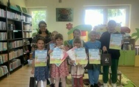 Uczestnicy konkursu stoją razem z Panią bibliotekarką trzymając swoje dyplomy
