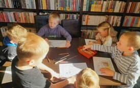 Dzieci przy stole kolorują jeżyki.