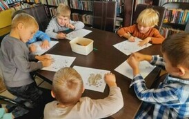 Chłopcy przy stole kolorują kolorowanki -  wiewi&oacute;rkę i jeżyka.