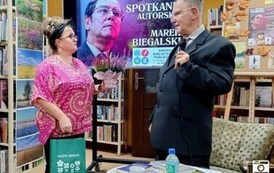 Kierowniczka biblioteki trzyma w rękach kwiatek doniczkowy i torebkę z upominkiem dziękując Panu Markowi za spotkanie.