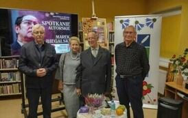 Trzech czytelnik&oacute;w stoi razem z Panem Markiem przy stoliku.