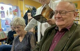 Jeden z czytelnik&oacute;w stoi wśr&oacute;d słuchających i czyta wiersz.