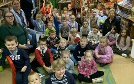 Dzieci siedzą na dywanie z aktorami i ze swoimi wychowawcami.