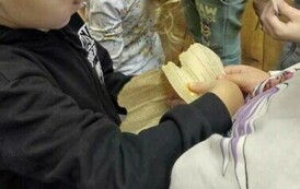 Dzieci stoją obok siebie trzymając swoje wydarte ze starych kartek serduszka