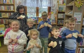 Dzieci stoja w grupie razem z Pania pedagog i pokazują swojewydarte serduszka ze starego papieru od książki.
