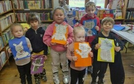 Dzieci stoją razem w grupie pokazując swoje wyklejone na kartkach misie z gazet.