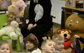 Dzieci siedzą przy Pani, kt&oacute;ra jest przebrana za misia i się uśmiecha.
