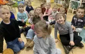 Dzieci siedzą  na siedziskach  w bibliotece.