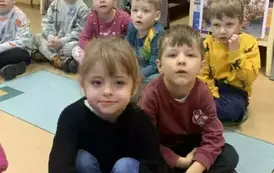 Dzieci siedzą  na siedziskach  w bibliotece.