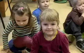 Dzieci siedzą  na siedziskach  w bibliotece.