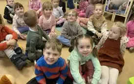 Dzieci siedzą  na siedziskach i słuchają bajki, niekt&oacute;re z nich się uśmiechają.