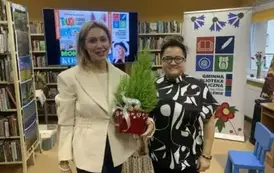 Kierowniczka biblioteki stoi przy pisarce, kt&oacute;ra trzyma udekorowaną choineczkę, kt&oacute;rą dostała w przezencie.