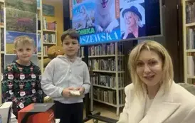 Dw&oacute;ch chłopc&oacute;w stoi w kolejce do pisarki po zakup książki i autograf.