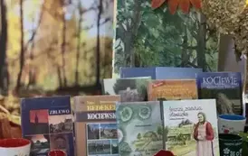 Na biurku wystawione są książki o tematyce kociewskiej, porcelanowe maki i kubek ze wzorem kociewskim.
