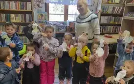 Dzieci stoją w grupie ze swoją Panią i trzymają w ręku pokolorowane dinozaury.