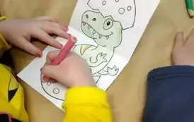 Ręce dzieci kolorujące dinozaury