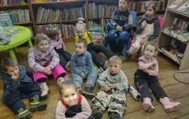 Dzieci siedzą na siedziskach i słuchają bajki.