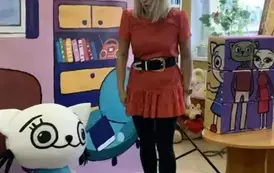 Na tle bajkowego pokoju bohaterka bajki Bajanka m&oacute;wi coś ze zdziwioną miną do Kici Koci, kt&oacute;ra stoi obok. Na stoliku po prawej stronie są duże klocki Kici Koci.