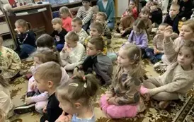 W bardzo licznej grupie siedzą dzieci na dywanie i patrzą na przedstawienie.