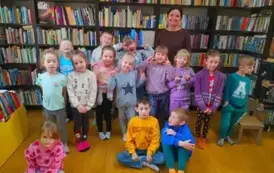 Dzieci stoją w grupie razem z bibliotekarką.