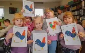 Pięć dziewczynek pokazuje swoje obklejone plasteliną na kartkach kolorowe koguciki.