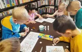 Dzieci przy stole uzupełniają zwierzątkowe sudoku naklejając odpowiednie elementy w puste kwadraciki.